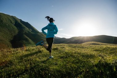 Genç kadın ultra-maraton koşucusu dağın tepesinde koşuyor.