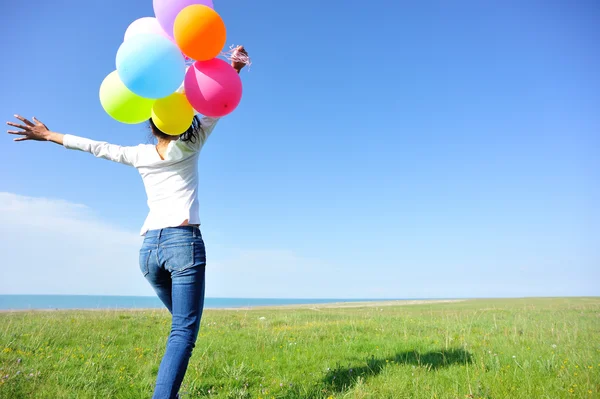 Mujer joven corriendo con globos de colores — Foto de Stock