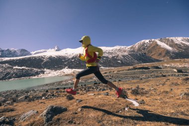 Yüksek rakımlı kış dağlarında koşan bir kadın.