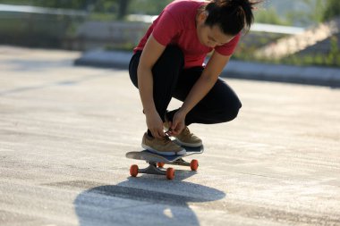 Dışarıda ayakkabı bağı bağlayan kaykaycı.