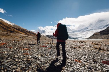 Kışın yüksek irtifa dağlarında yürüyüş yapan iki kadın yürüyüşçü.