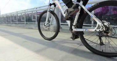 Köprüde bisiklet süren bir kadın.