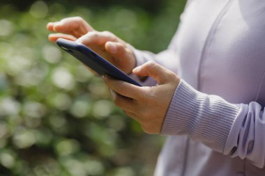 Açık havada akıllı telefon kullanan Asyalı kadın.