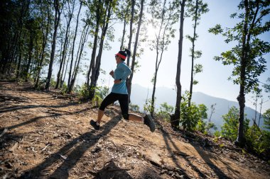 Gündoğumunda tropik orman zirvesinde koşan fitness kadın patika koşucusu