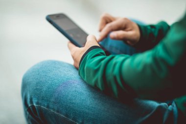 Açık havada akıllı telefon kullanan Asyalı kaykaycı kadın.