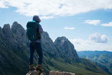 Başarılı bir kadın sırt çantalı dağ zirvesinde yürüyüş yapıyor.