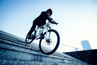 Şehir merdivenlerinden bisikletle inen bir kadın.