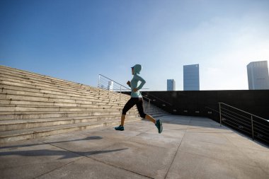 Spor salonundaki kadın Sunrise City 'de merdivenlerden yukarı koşuyor.
