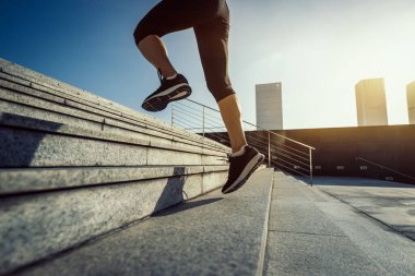 Fitness sporcusu kadın şehirde merdivenleri koşarak çıkıyor.