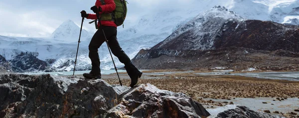 Woman backpacker hiking in winter high altitude mountains