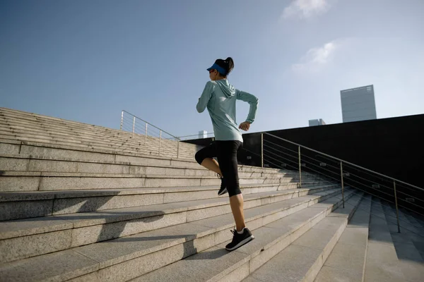 Fitness sporcusu kadın şehirde merdivenleri koşarak çıkıyor.