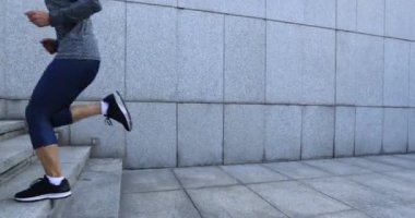 Genç bir kadın dışarıda merdivenlerde koşuyor.