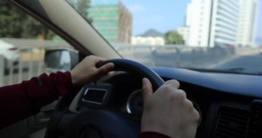 Kadın şehir yolunda araba sürüyor.