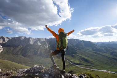 Başarılı bir kadın sırt çantalı dağ zirvesinde yürüyüş yapıyor.