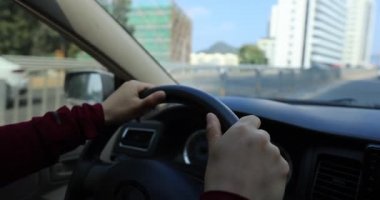Kadın şehir yolunda araba sürüyor.