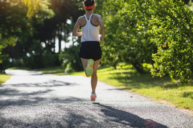Güneşli tropik park yolunda koşan fitness kadını