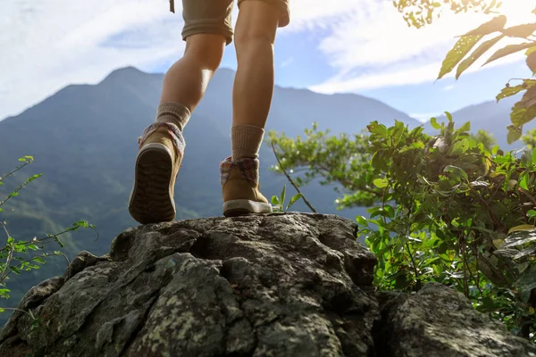 不屈不挠的女徒步旅行者的腿站在山顶岩石上 — 图库照片