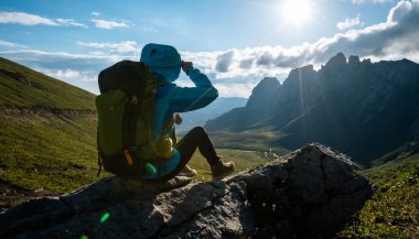Başarılı bir kadın sırt çantalı. Gün batımı dağlarının zirvesinde yürüyüş yapıyor.
