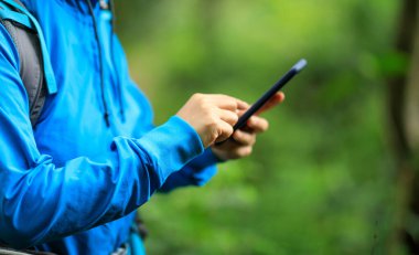 Spring Ormanı 'nda akıllı telefon kullanan bir kadın yürüyüşçü.