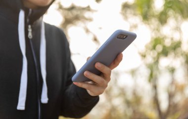 Kışın ormanda akıllı telefon kullanan bir kadın yürüyüşçü.