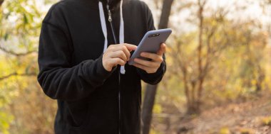 Kışın ormanda akıllı telefon kullanan bir kadın yürüyüşçü.