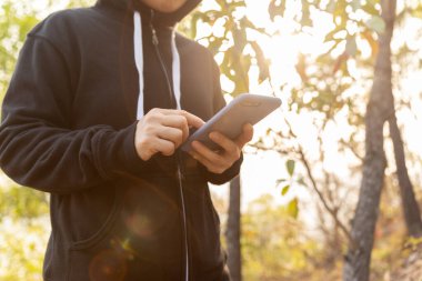 Kışın ormanda akıllı telefon kullanan bir kadın yürüyüşçü.