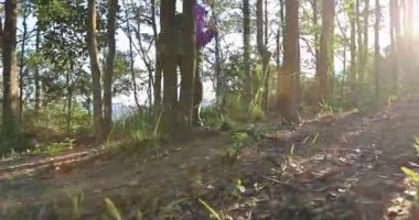 Sırt çantalı genç bir kadın ormanda yürüyüş yapıyor.