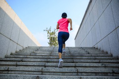 Fitness sporcusu kadın şehirde merdivenleri koşarak çıkıyor.