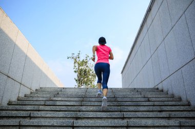 Fitness sporcusu kadın şehirde merdivenleri koşarak çıkıyor.
