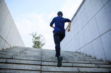 Şehirde merdivenlerden koşan sporcu kadın.