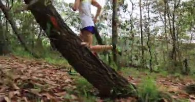 Kadın koşucu orman yolunda koşuyor.