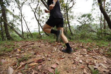 Kadın koşucu orman yolunda koşuyor.