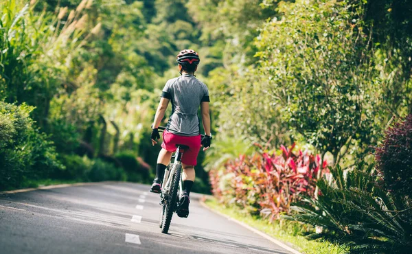 Tutmadan bisiklet süren bir kadın. Tropikal yaz parkı patikası.