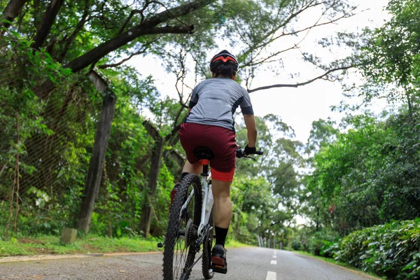 Güneşli bir günde parkta bisiklet süren bir kadın.