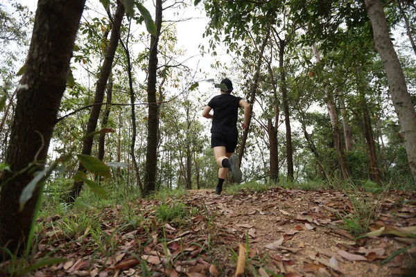 Kadın koşucu orman yolunda koşuyor.