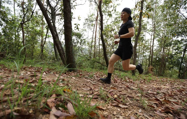 Kadın koşucu orman yolunda koşuyor.