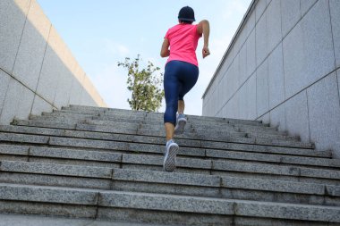 Fitness sporcusu kadın şehirde merdivenleri koşarak çıkıyor.