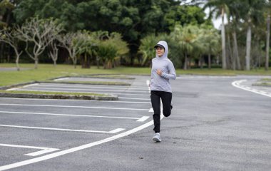 Tropik parkta koşan sağlıklı yaşam tarzı, sportif Asyalı kadın.