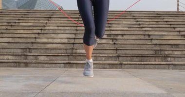 Genç sporcu kadın şehirde ip atlıyor.