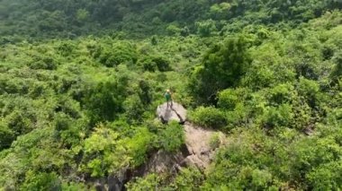 Kadın yürüyüşçü dağın tepesinde dikiliyor.