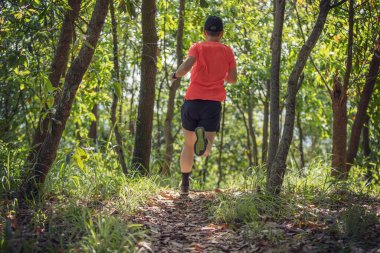 Kadın koşucu orman yolunda koşuyor.
