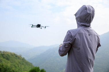 Bahar ormanlarında uçan dronu kontrol eden kadın.