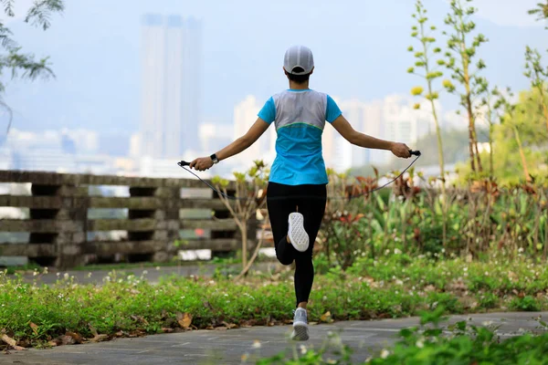 Asian woman skipping rope in park