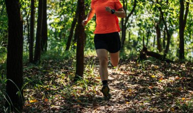 Kadın koşucu orman yolunda koşuyor.