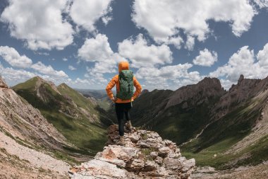 Başarılı bir kadın sırt çantalı. Gün batımı dağlarının zirvesinde yürüyüş yapıyor.