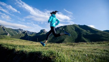 Genç kadın ultra-maraton koşucusu dağın tepesinde koşuyor.