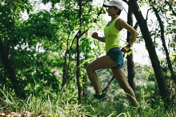 Woman runner running on forest trail