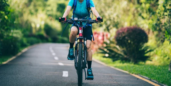 Woman cycling on tropical park trail in summer