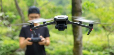 People remote control a flying drone in summer forest