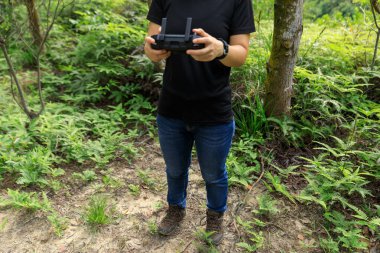 People remote control a flying drone in summer forest